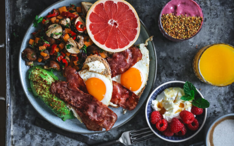 Søndagsbrunch med egg, bacon, toast, grønnsaker, frukt og bær